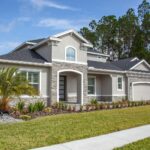 Beautiful modern suburban house in Odessa, FL with lush garden and clear blue sky.